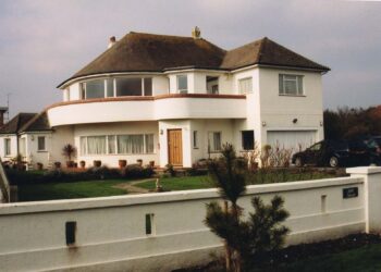 Colour photograph of a white house with brown roof. 